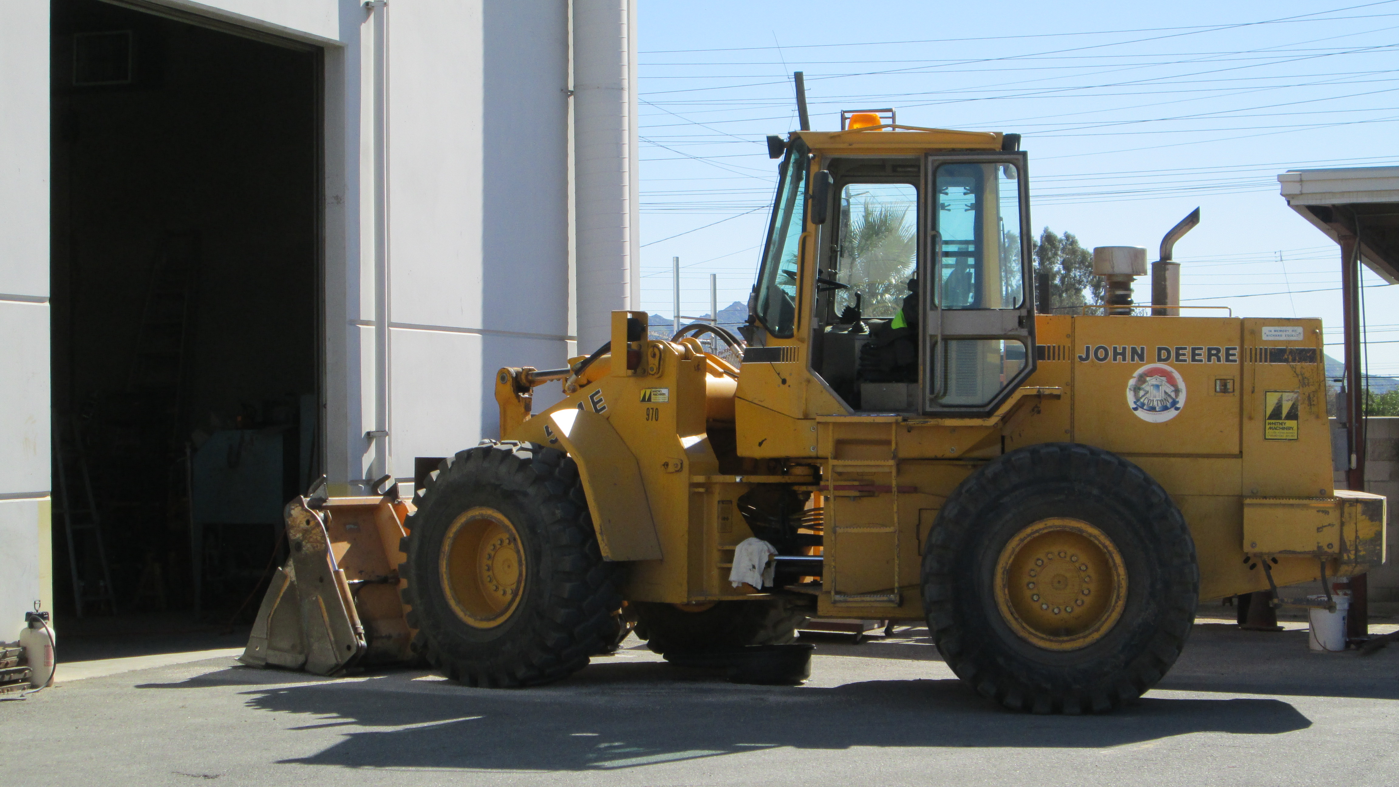 A large piece of construction equipment parked outside of a large garage facility
